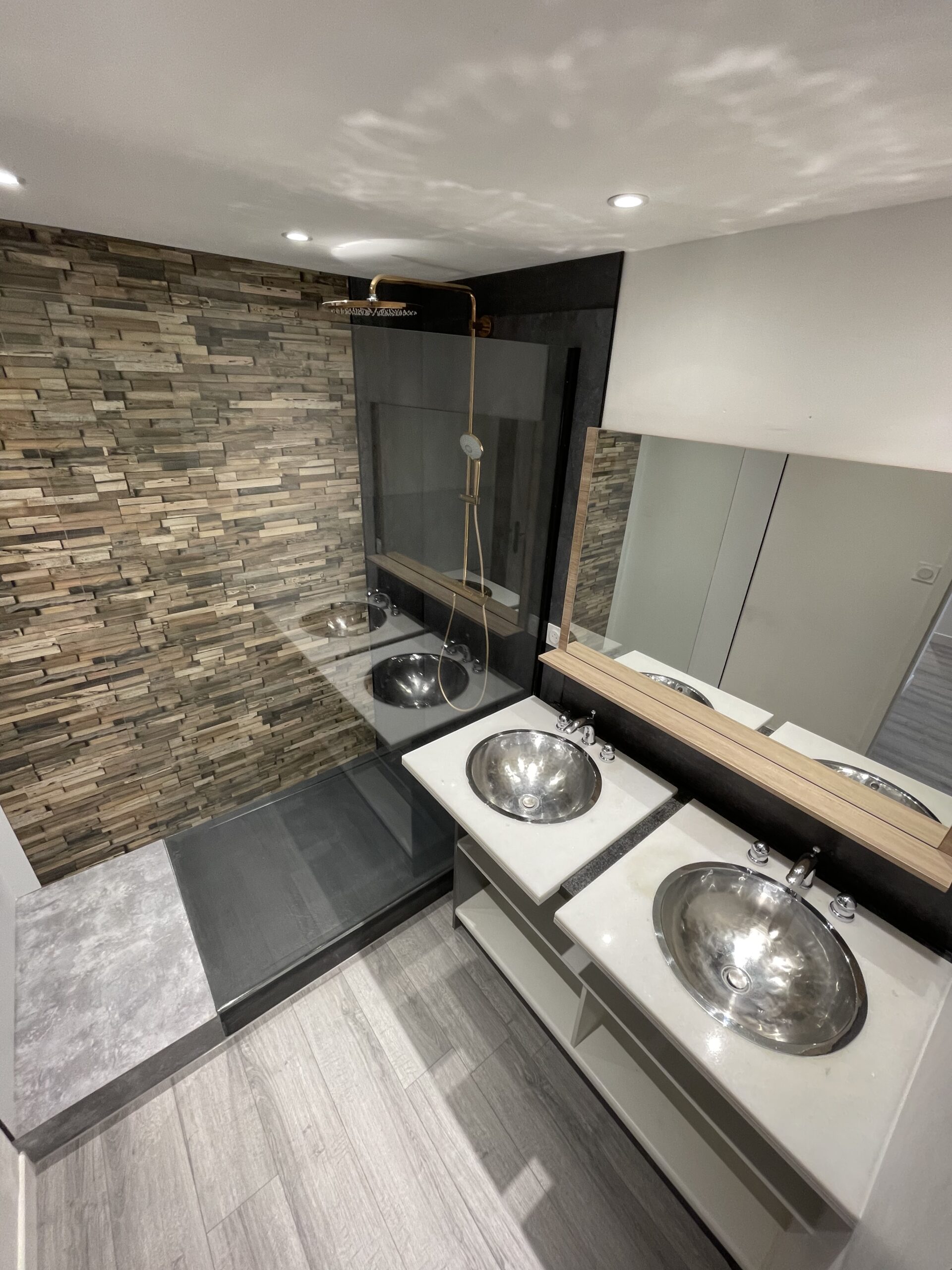 Rénovation salle de bain au style moderne avec double vasques encastrées dans plan en marbre. Panneaux de douche imitation bois.