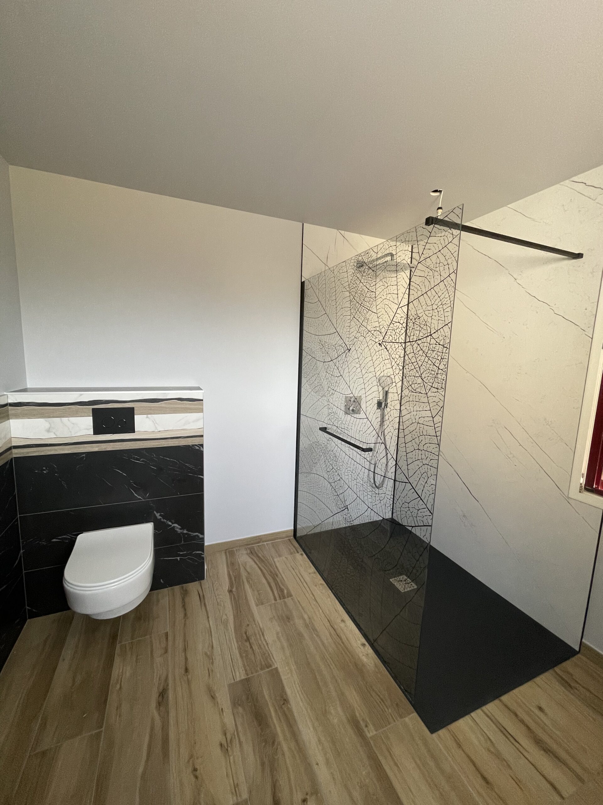 Rénovation salle de bain avec douche à l'italienne, paroi de douche à motif feuille et robinetterie encastrée.
